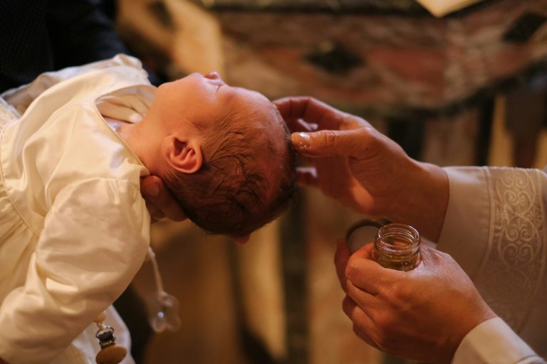 A baby is being fed a glass of wine